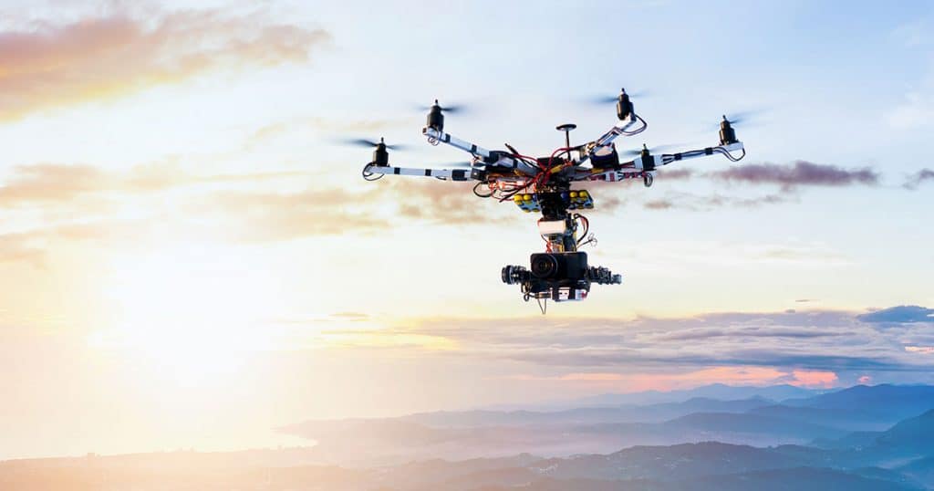 UAV flying over mountains carrying SKYTRAC's DLS-100™ at sunset