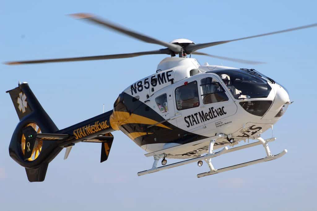 STAT MedEvac helicopter flying with blue sky background.