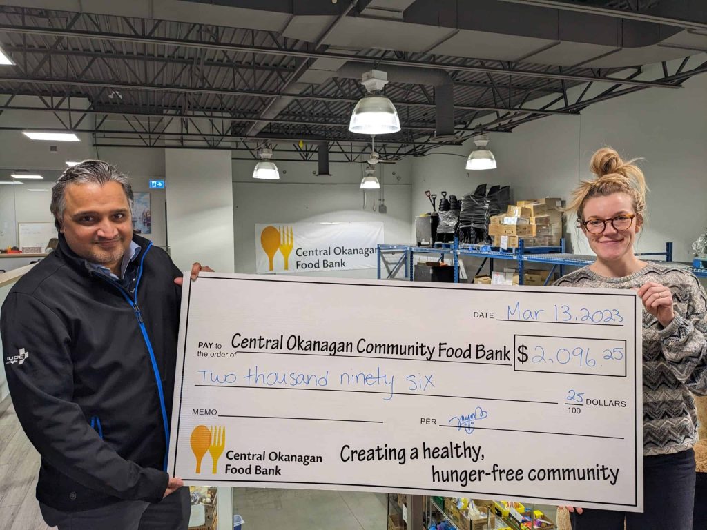Jayant Singh of SKYTRAC and Rayann Gruza of the Central Okanagan Community Food Bank pose with a giant cheque depicting the $2096.25 donation raised by SKYTRAC employees.