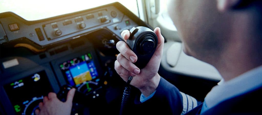 A pilot speaking into a push to talk radio in an airplane