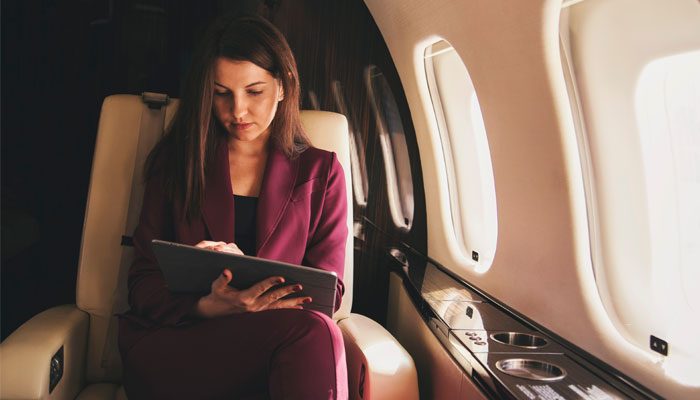 Business Women in Private Jet Using a Tablet That is Connected to Broadband Internet Using SKYTRAC Satcom Services