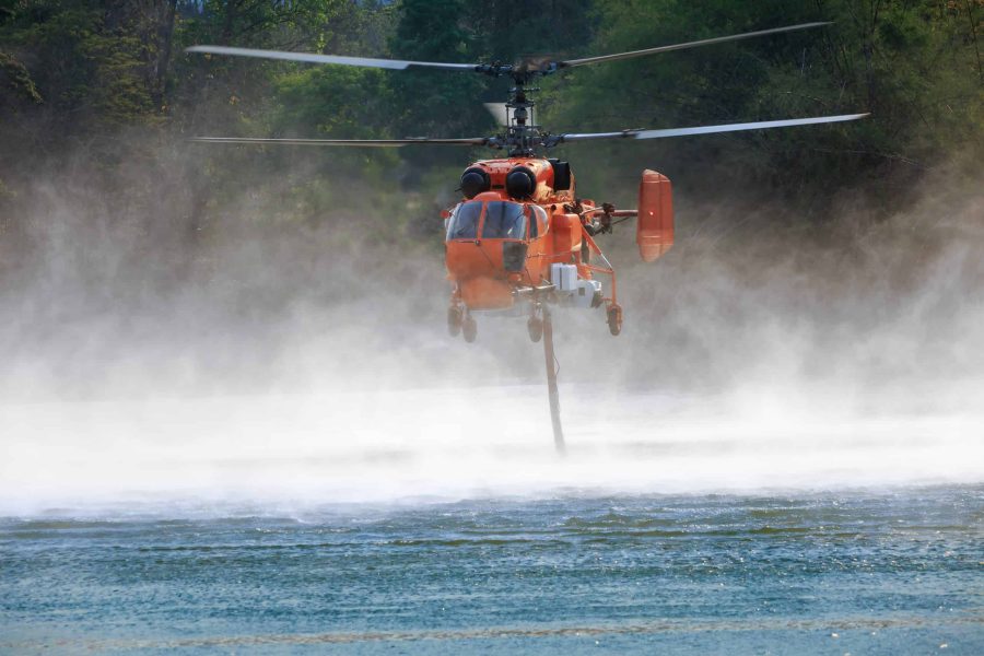 Firefighting helicopter is hovering over the pond refill water