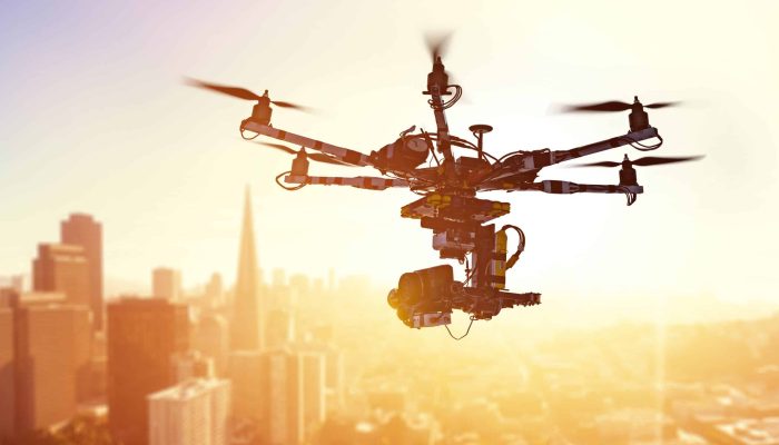 Innovation photography concept. Silhouette drone Flying over San-Francisco city on blurred background. Heavy lift drone photographing city at sunset.