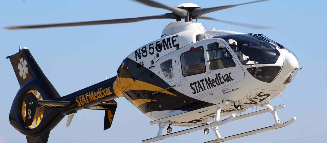 STAT MedEvac helicopter flying with blue sky background.